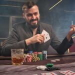 Cheeky brunette man in a classic suit is playing poker sitting a