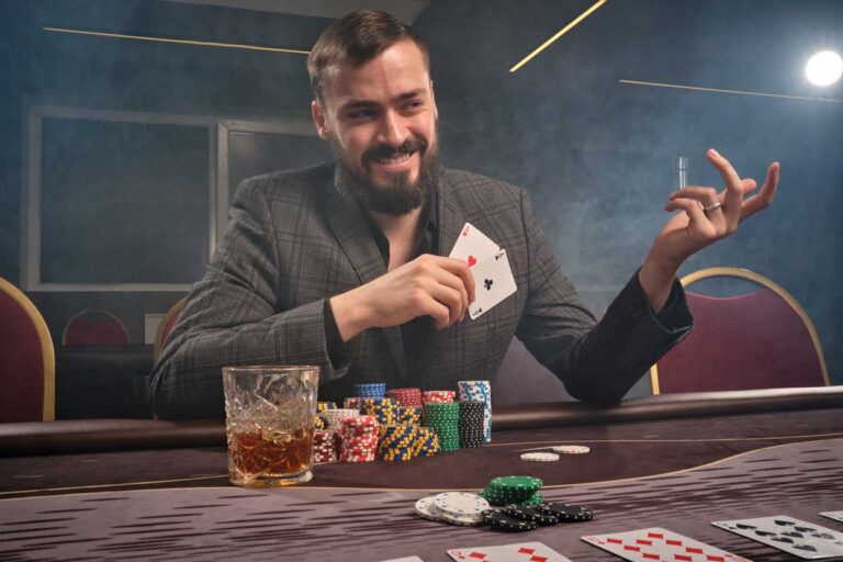 Cheeky brunette man in a classic suit is playing poker sitting a