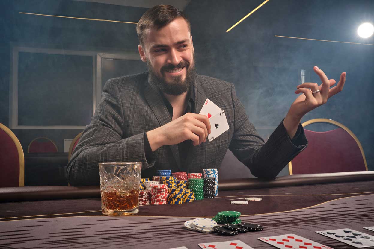 Cheeky brunette man in a classic suit is playing poker sitting a